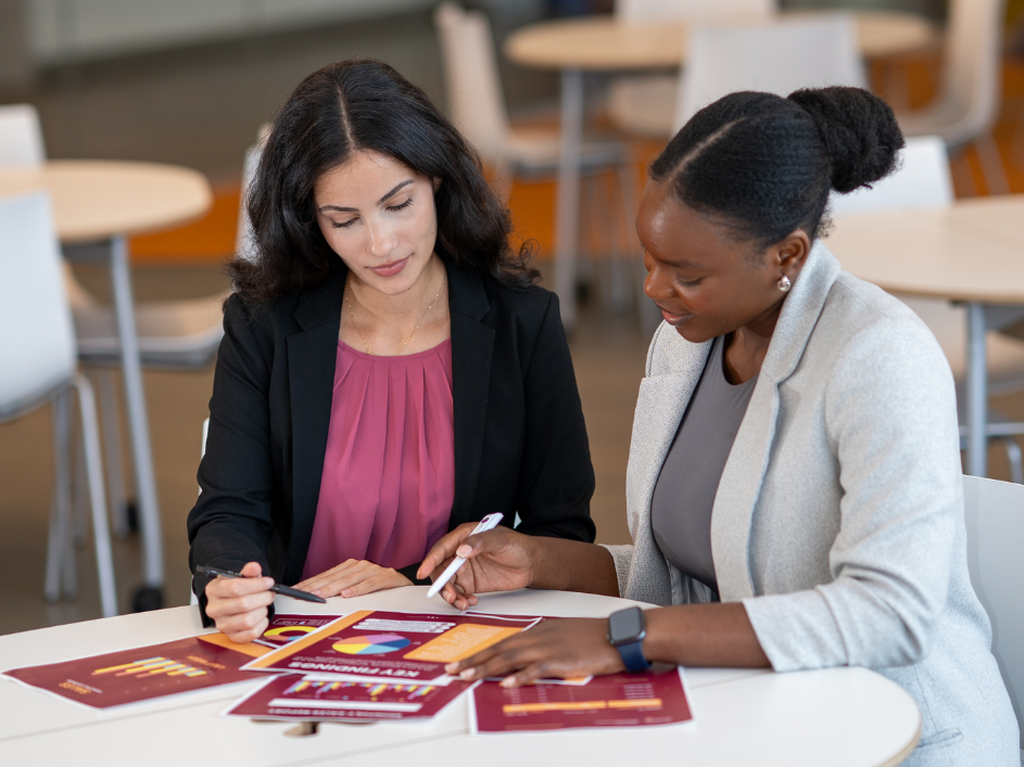 An advisor consulting a student with documents at a table.