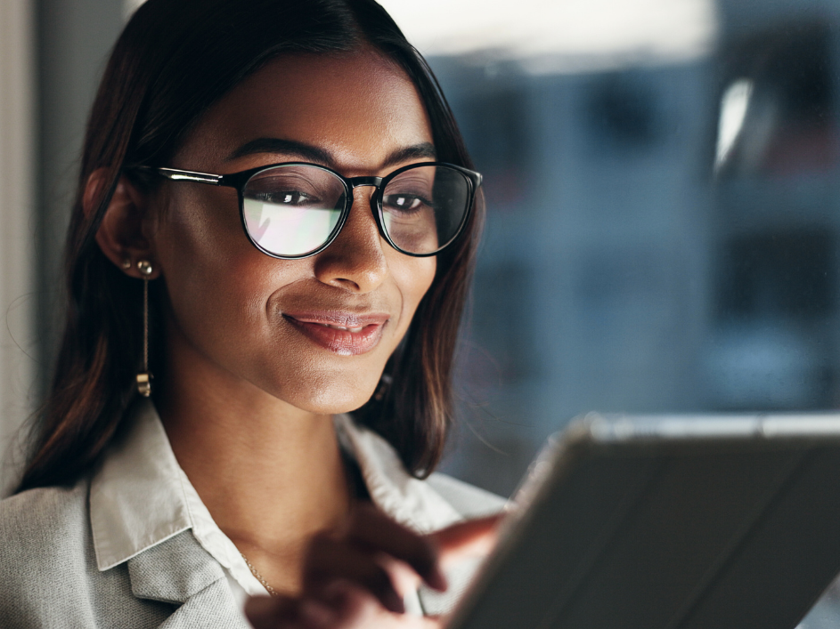 A student smiling, looking through a tablet.